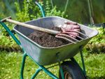Wheelbarrow In The Garden Full Of Soil And Gardening Tools