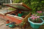 Cold Frame In Garden Next To Potted Plants And Garden Tools