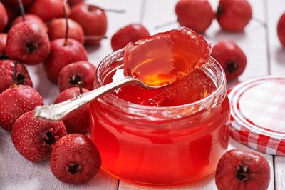 Jar Of Red Jelly Surrounded By Mayhaw Fruit
