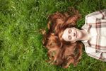 Red Headed Lady Laying On Green Grass