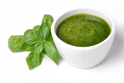 Small Cup Of Superbo Basil Mixture Next To Whole Basil Leaves