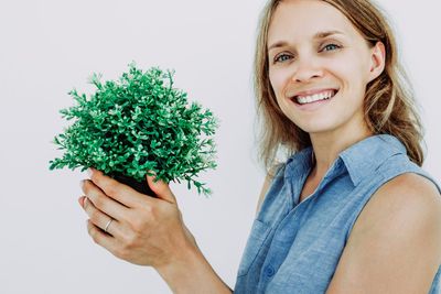 Person Smiling And Holding A Tiny Potted Plant