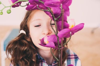 Little Girl Smelling Orchid Flower at Home