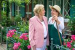 Two Ladies Talking Infront Of Beautiful Flower Gardens