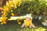 Baby Sitting In Garden With Yellow Flowers