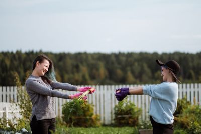 Two Women In The Garden Holding Vegetables