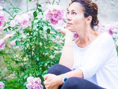 Woman Sitting In A Garden By Flowers
