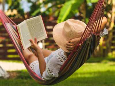 Person In The Backyard Lying In A Hammock Reading A Book