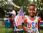 Little Boy Holding An American Flag At A BBQ