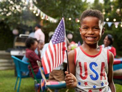 Little Boy Holding An American Flag At A BBQ
