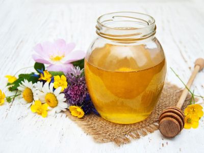 Jar Of Honey Next To Flowers