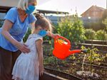 Adult With Child Watering Garden With Watering Can