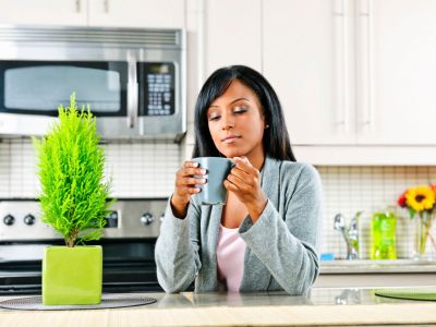 Woman In A Kitchen Next To A Green Potted Plant
