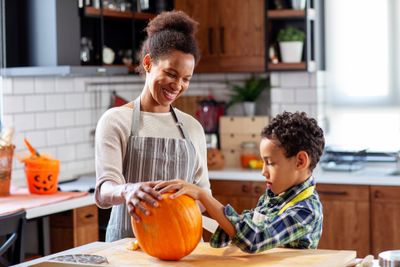Woman And Child Carving Pumpkins In A Kitchen