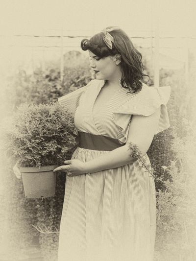 Old-Fashioned Photo Of Woman In Garden Holding A Plant
