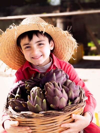 Child Holding A Basket Of Artichokes