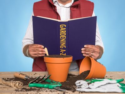 Person Reading A Gardening Book With Pots  Soil  And Gardening Tools