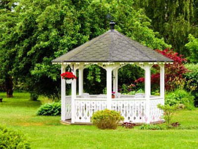 A White Gazebo In The Landscape Surrounded By Plants And Flowers