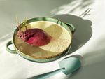 A red potato in a bowl of water sprouts roots and leaves