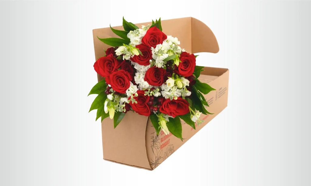 A red and white bouquet in a shipping box.