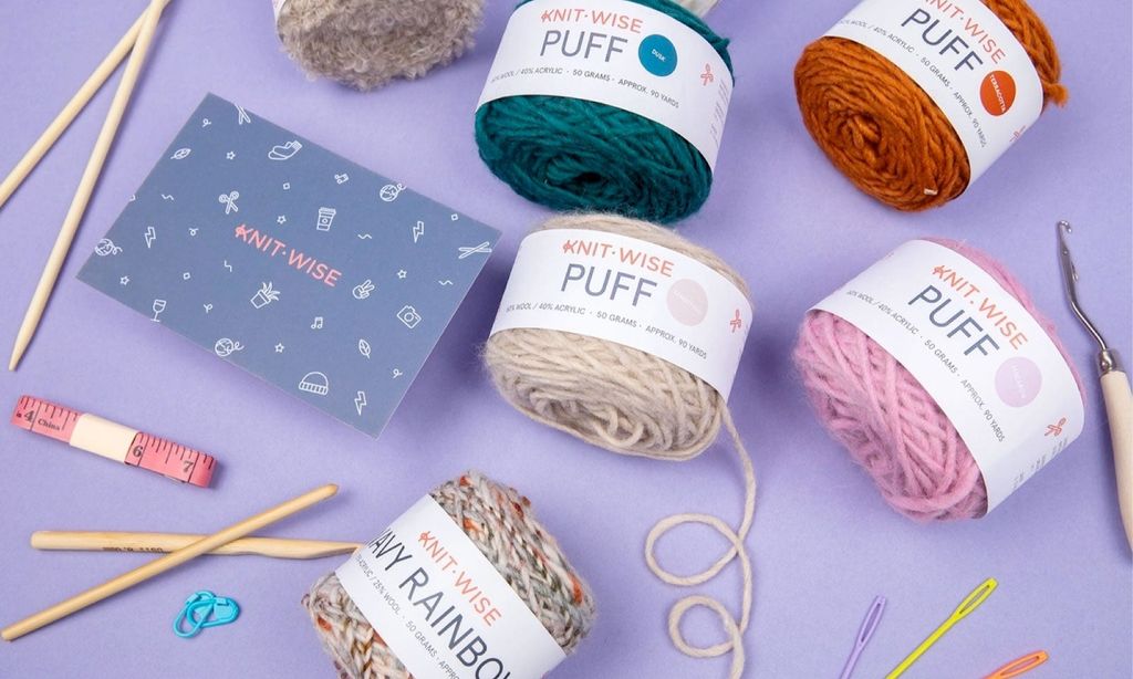 Five spools of yarn with knitting needles and a gift box