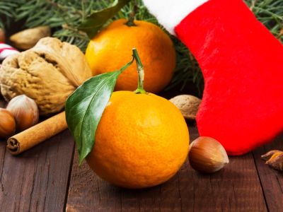 An orange with a leaf attached to the stem next to Christmas themed items