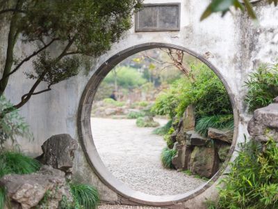 A stone wall with a circular opening in a garden