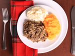 Haggis, mashed potatoes, and mashed turnips on a plate with a red tartan napkin