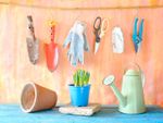 Garden gloves and tools hang over a watering can and flower pots