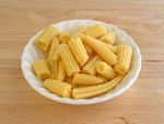 A small white bowl full of baby corn