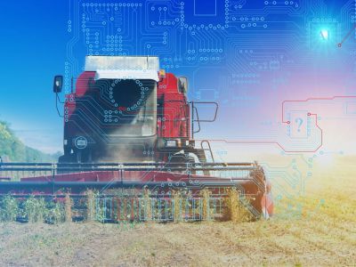 A piece of farm machinery works in a field with AI written over it