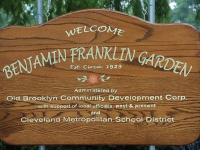 A wooden sign that says "Welcome Benjamin Franklin Garden"