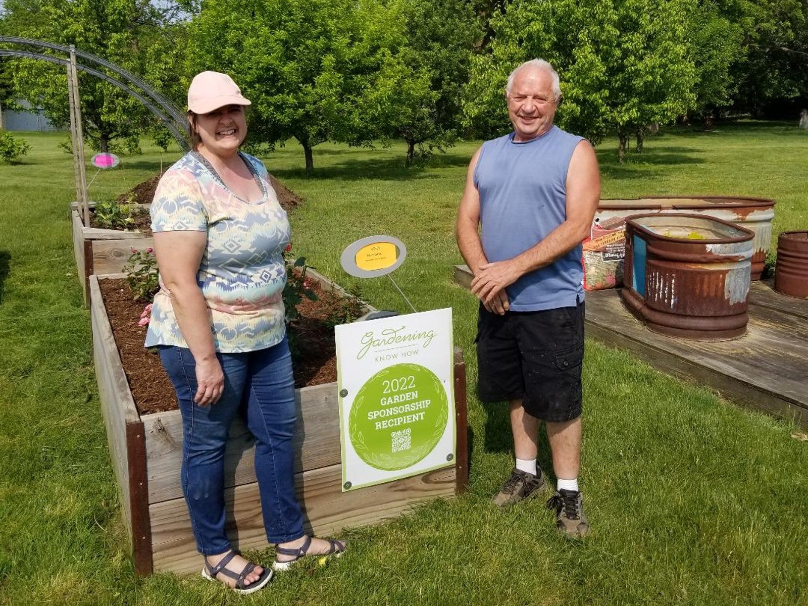 A man and woman smile next to a raised garden bed