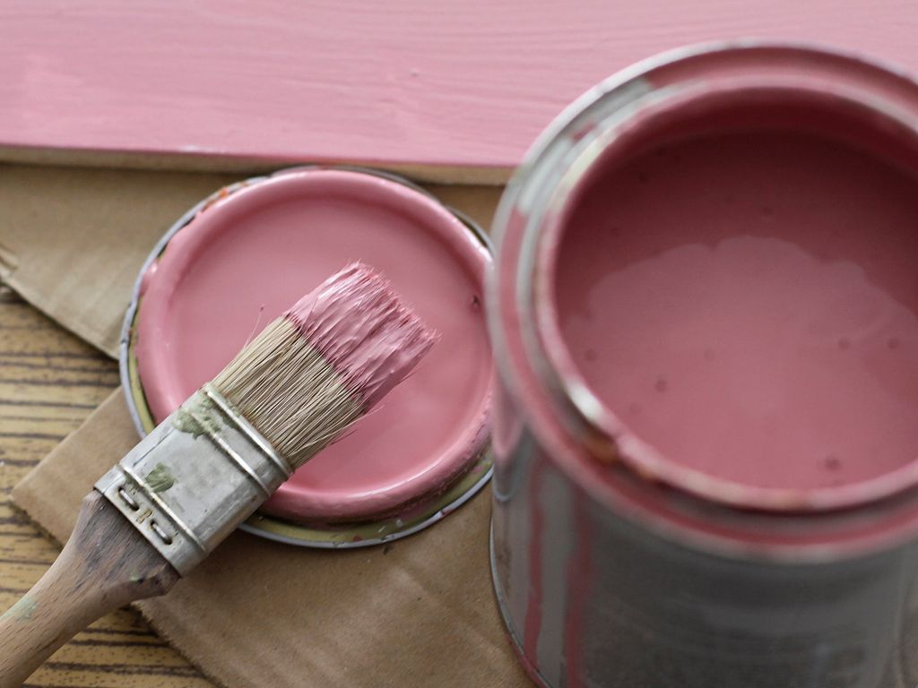 Pink paint can with brush on pink background