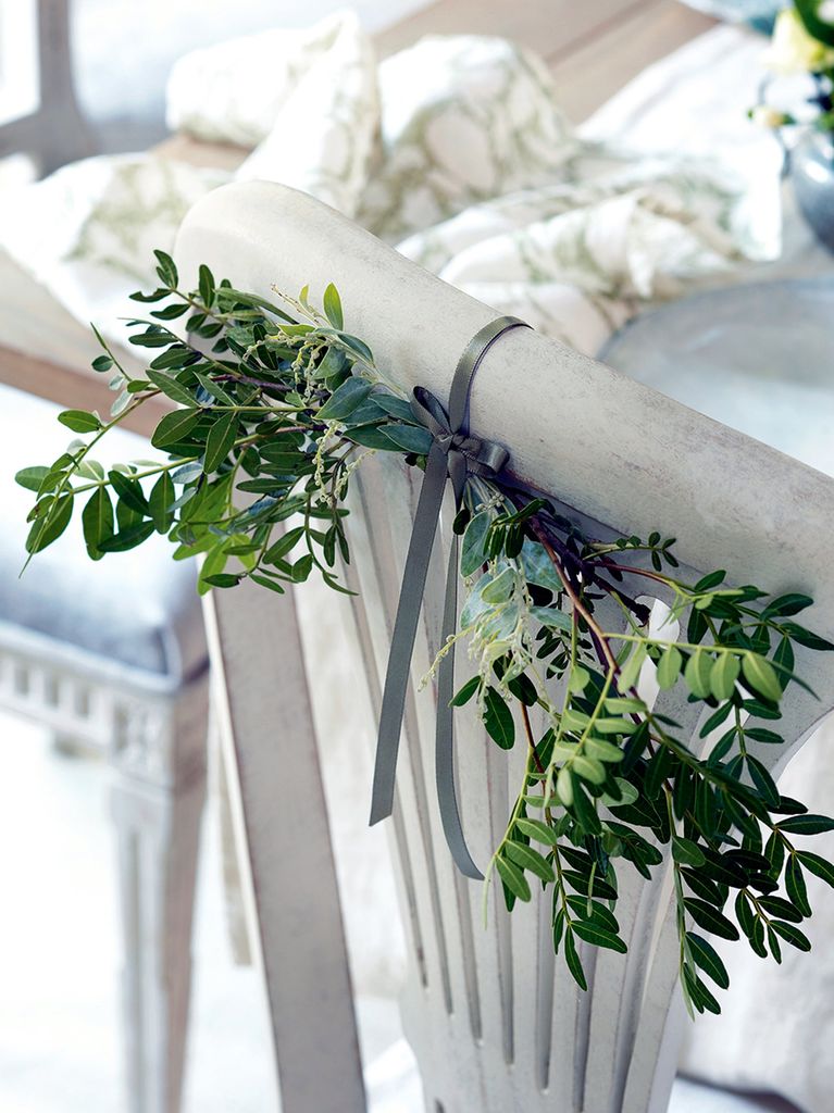 Wooden chair with foliage swag tied to the back using grey ribbon