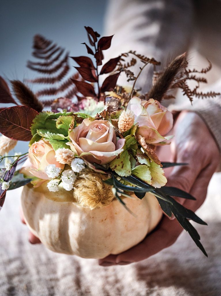 Gourd hollowed out to make a vase, filled with pretty flowers and foliage